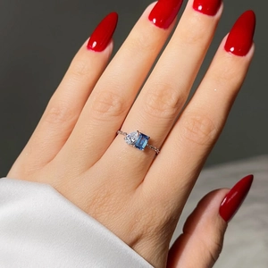 Detail of Toi et Moi gold chain ring with emerald cut blue stone and teardrop crystal