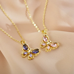 Elegant gold butterfly pendant necklace with blue and pink gemstones on silk background