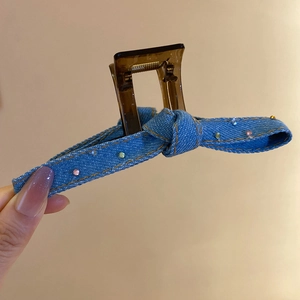 Detail of denim bow hair claw clip with colorful rhinestones on brown acrylic base