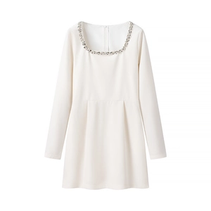 Detail of elegant white velvet dress featuring exquisite hand-beaded rhinestone neckline
