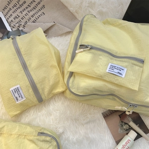 Close-up of light yellow plaid travel organizers on plush white carpet texture
