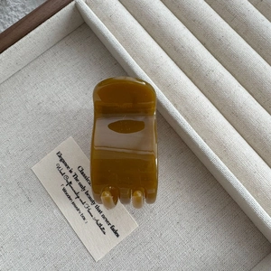 Detailed view of an amber brown 5cm hair claw clip on a luxury display tray