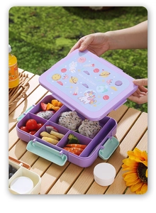 Close-up of kids bento box with space theme and sections for fruit, rice balls, and shrimp