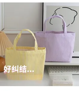 Detail of yellow and purple striped canvas tote bags in a cozy desktop setting