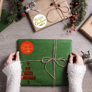 Macro view of gold foil Merry Christmas gift stickers on a festive wooden table