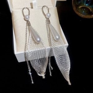 Detail of silver drop earrings featuring mesh leaf design, pearl accents, and fine tassels