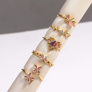 Détail d'un lot de cinq bagues dorées avec pierres roses et motifs de couronnes florales