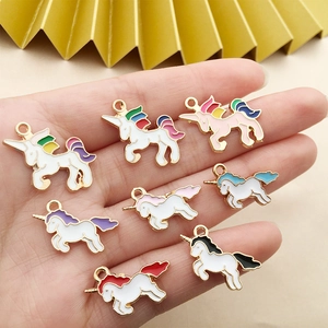 Detailed close-up of colorful enamel unicorn charms held in palm for DIY jewelry making