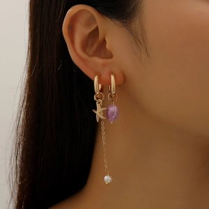 Asymmetric gold earrings with starfish pearl chain and purple bead on female model