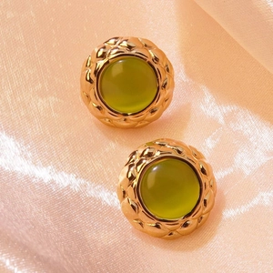 Macro detail of vintage gold stud earrings featuring green stone and woven edge texture