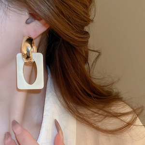 Close-up of geometric resin drop earring with gold metal ring on model's ear