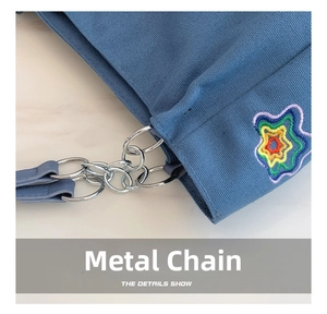 Detail of blue canvas bag featuring colorful star embroidery and silver hardware chain