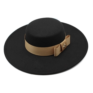 Close-up of black wool boater hat with camel ribbon and golden bee ornament detail