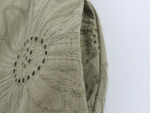 Macro shot of olive green embroidered hollow-out cotton-linen fabric and textured sewing