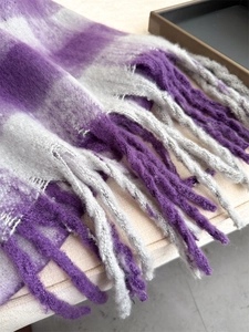 Detailed texture of thick purple and grey plaid scarf with long soft tassels fringe