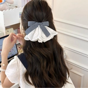 Close-up of a blue linen bow hair clip with white lace trim worn on long hair