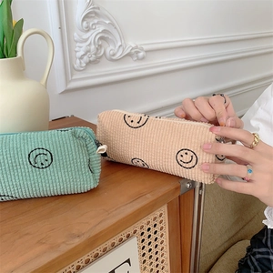 Detail of vintage corduroy makeup bags in green and beige featuring cute smiley faces