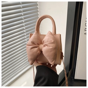 Close-up of pink PU leather handbag with a large bow detail and elegant texture