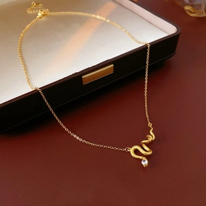 Macro shot of gold-plated snake pendant with white gemstone on dark leather