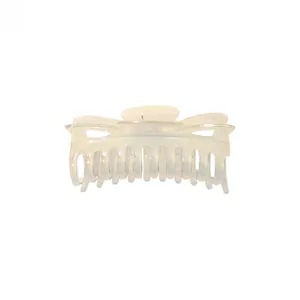 Detail of large iridescent pearlescent hair claw clip with twisted bow design on white background