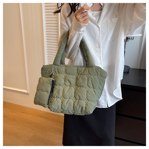 Detail of green quilted tote bag showing pebble texture and small matching pouch charm