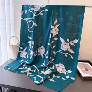 Detail of silk-like blue scarf with white rose print draped over a metal stand