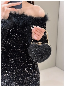 Macro shot of heart-shaped evening bag with black rhinestones and gold metal handle