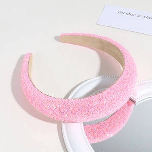 Detail view of a pink glitter sponge headband on a mirror with sparkling sequins textures