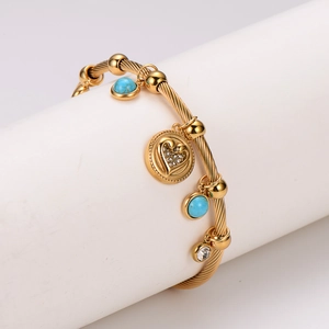 Golden stainless steel heart bracelet with turquoise bead on white display stand