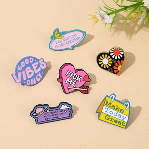 Close-up of 6 colorful enamel metal pins with heart and quote designs on beige background