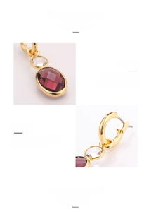 Macro detail of gold-plated hoop earrings featuring faceted purple crystal glass stones