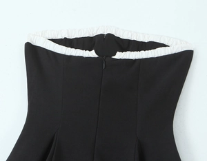 Detail view of the back zipper and white ruffled trim on the black tube dress