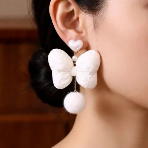 Elegant white bow earrings with pearl accents and plush ball drops for a stylish look