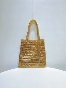Detailed view of the woven golden beaded texture and shimmering sequins on the handbag
