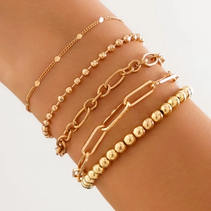 Detail of four-piece gold bracelet set featuring heart pendant and beaded layers