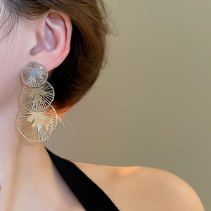 Gros plan de boucles d'oreilles frangées en argent à trois niveaux avec motifs ronds
