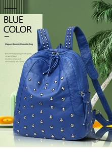 Close-up of blue pebbled leather backpack with silver rivets and metal zipper details