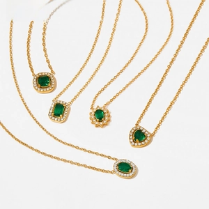 Detailed shot of five gold necklaces featuring emerald-green stones and white zircon halos