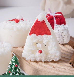 Detail of Christmas candles featuring Santa, mini tree, and cake on a wooden tray