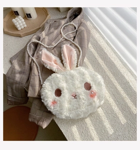 Macro detail of white plush rabbit bag with pearl chain strap and soft faux fur texture