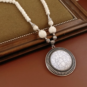Detail of vintage silver relief pendant with white marble beads on ethnic necklace