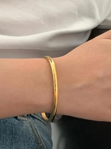 Close-up of polished gold-plated stainless steel cuff bracelet on wrist