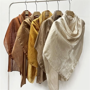 Close-up of silky satin scarves in earth tones hanging elegantly on a white background