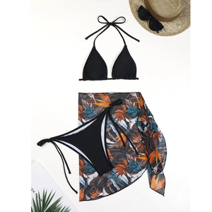 Detailed flat lay of a 3-piece bikini set with tropical floral print sarong and beach accessories