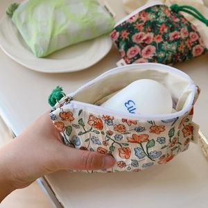 Détail d'une mini pochette en coton floral avec fermeture éclair et tirette tissée
