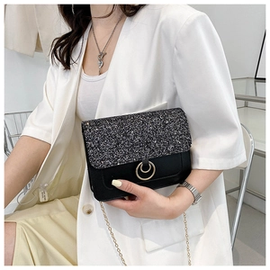 Detail shot of a black crossbody bag with silver sequins and a gold double ring clasp