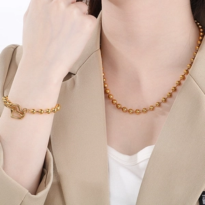 Gold stainless steel beaded necklace and heart-shaped OT clasp bracelet set on model