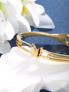 Macro detail of golden butterfly bracelet featuring frosted texture and sparkling zircons