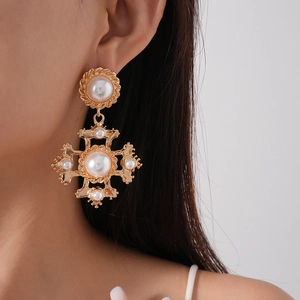 Detail of vintage gold cross earrings with baroque pearls on model for a royal aesthetic