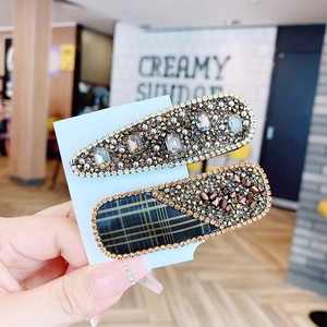 Close-up of sparkling rhinestone hair clips held in hand with cafe background